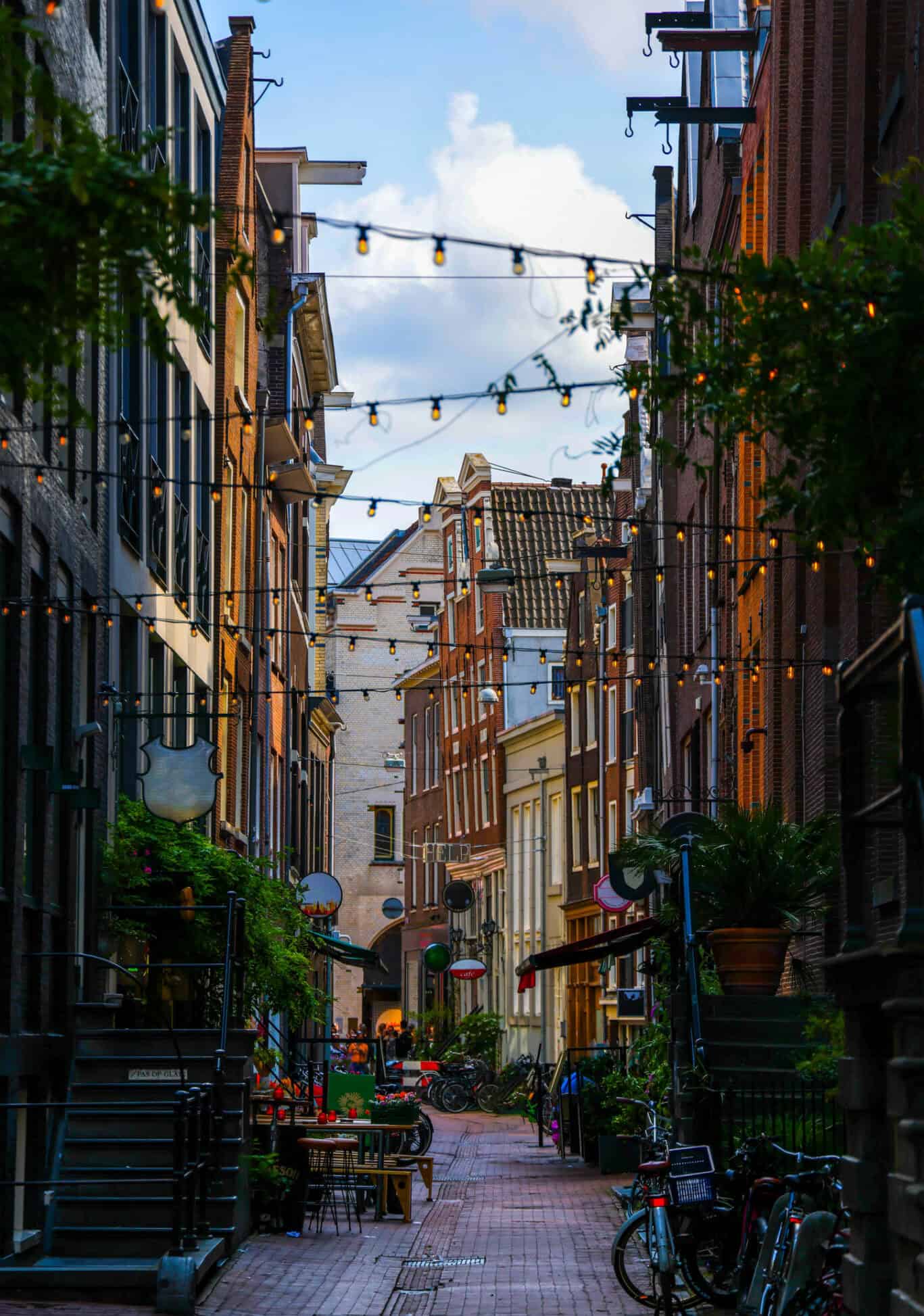 A cosy street scene near The Flying Pig Downtown hostel in Amsterdam with string lights and bicycles.