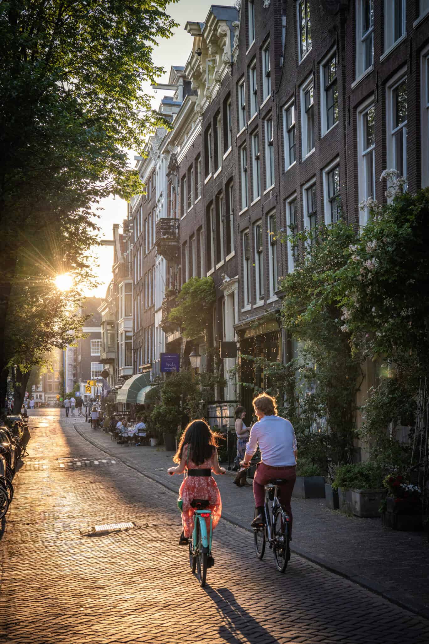 A woman and a girl cycling on a city street near The Flying Pig Downtown hostel in Amsterdam.