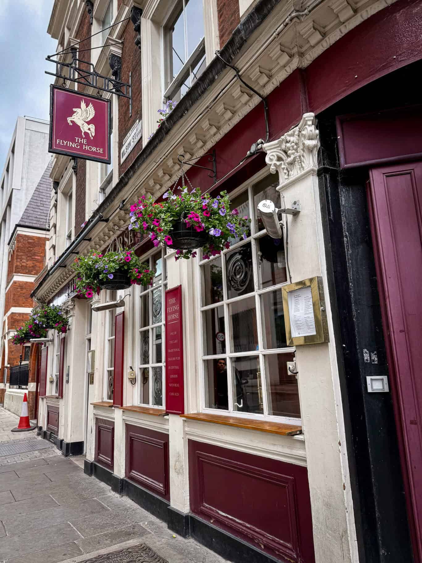 Historic pub facade with hanging flower baskets and classic signage in Liverpool Street.