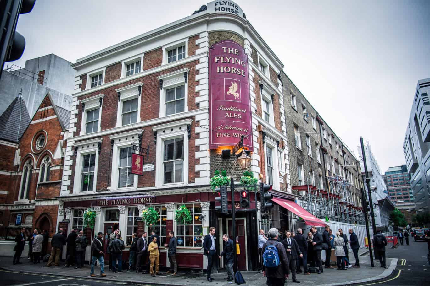 Historic pub exterior with red brick facade and large windows.