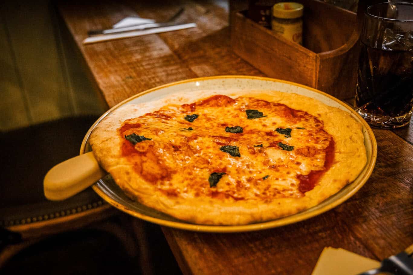 Delicious Margherita Pizza with fresh basil on a wooden table.