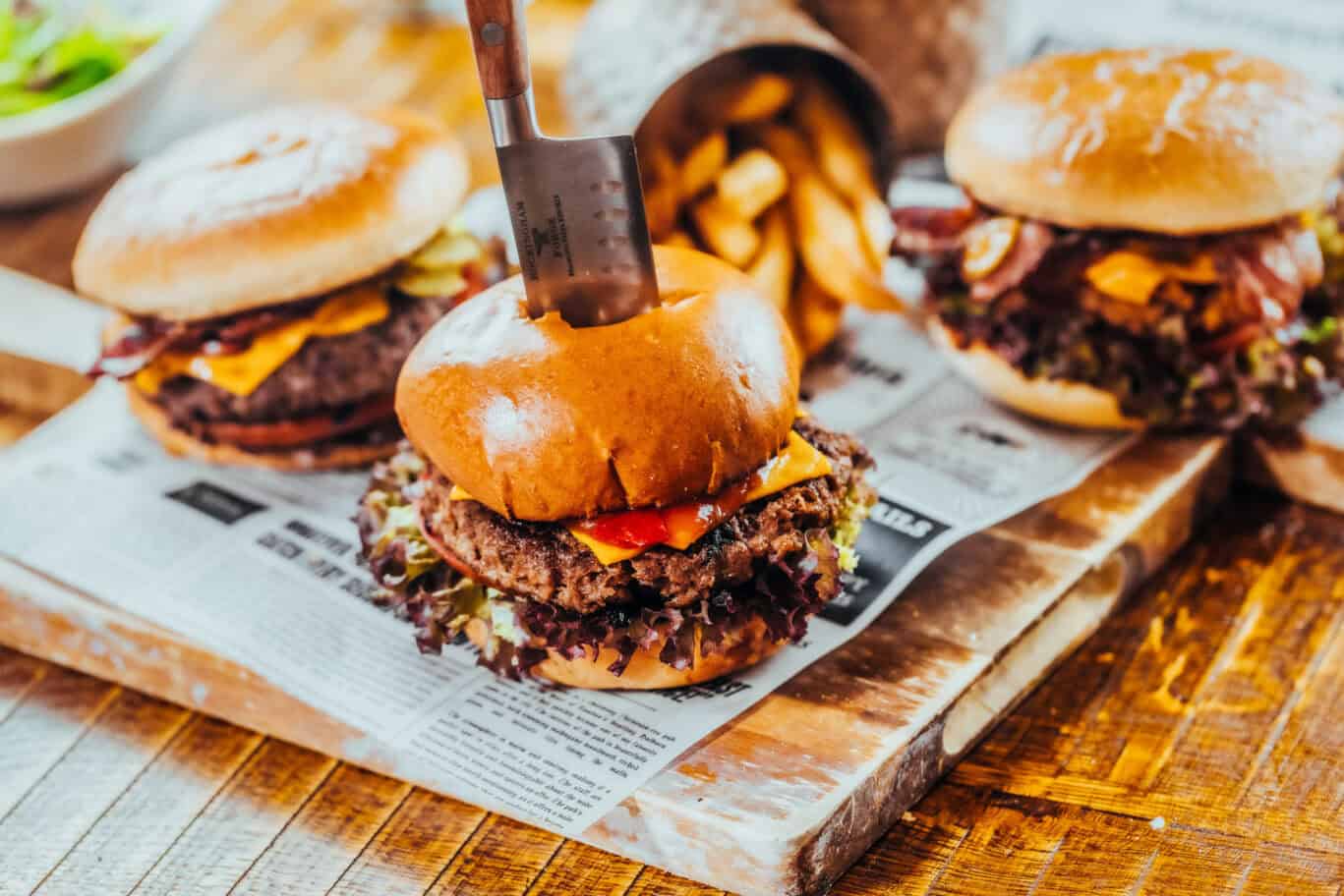 A vibrant image of delicious gourmet burgers with fries on a rustic wooden table at St Christopher’s.
