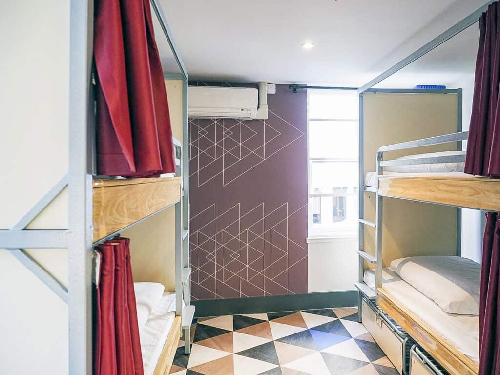 Bunk beds with privacy curtains in a compact hostel dorm at Liverpool Street.