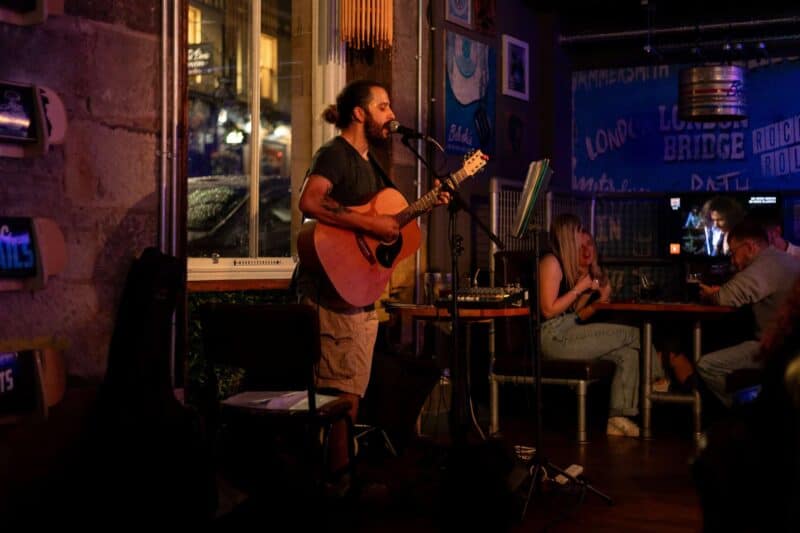 A musician with a guitar performing live music at St Christopher’s Liverpool Street hostel.