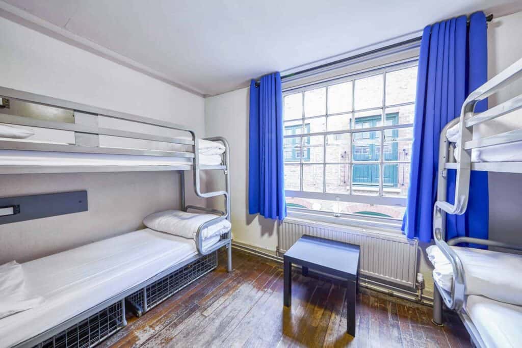 Bunk-bed room at St Christopher's Inn London Bridge - The Inn with a large window and blue curtains.