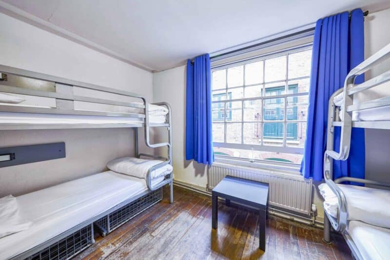 Bunk-bed room at St Christopher's Inn London Bridge - The Inn with a large window and blue curtains.