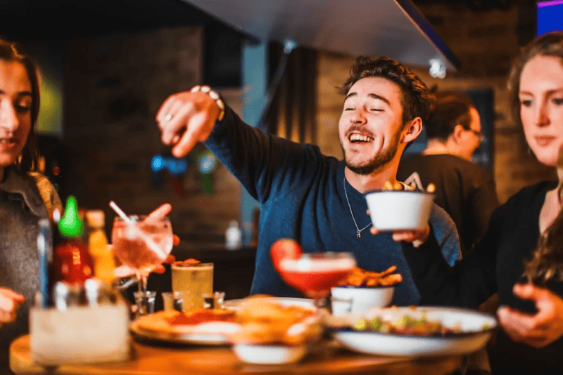 People enjoying food and drinks at London Bridge Hostel bar.