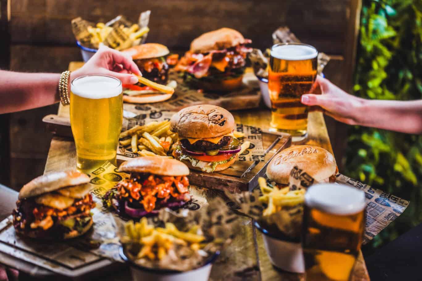 People enjoying burgers and beers at London Bridge Hostel dining area.