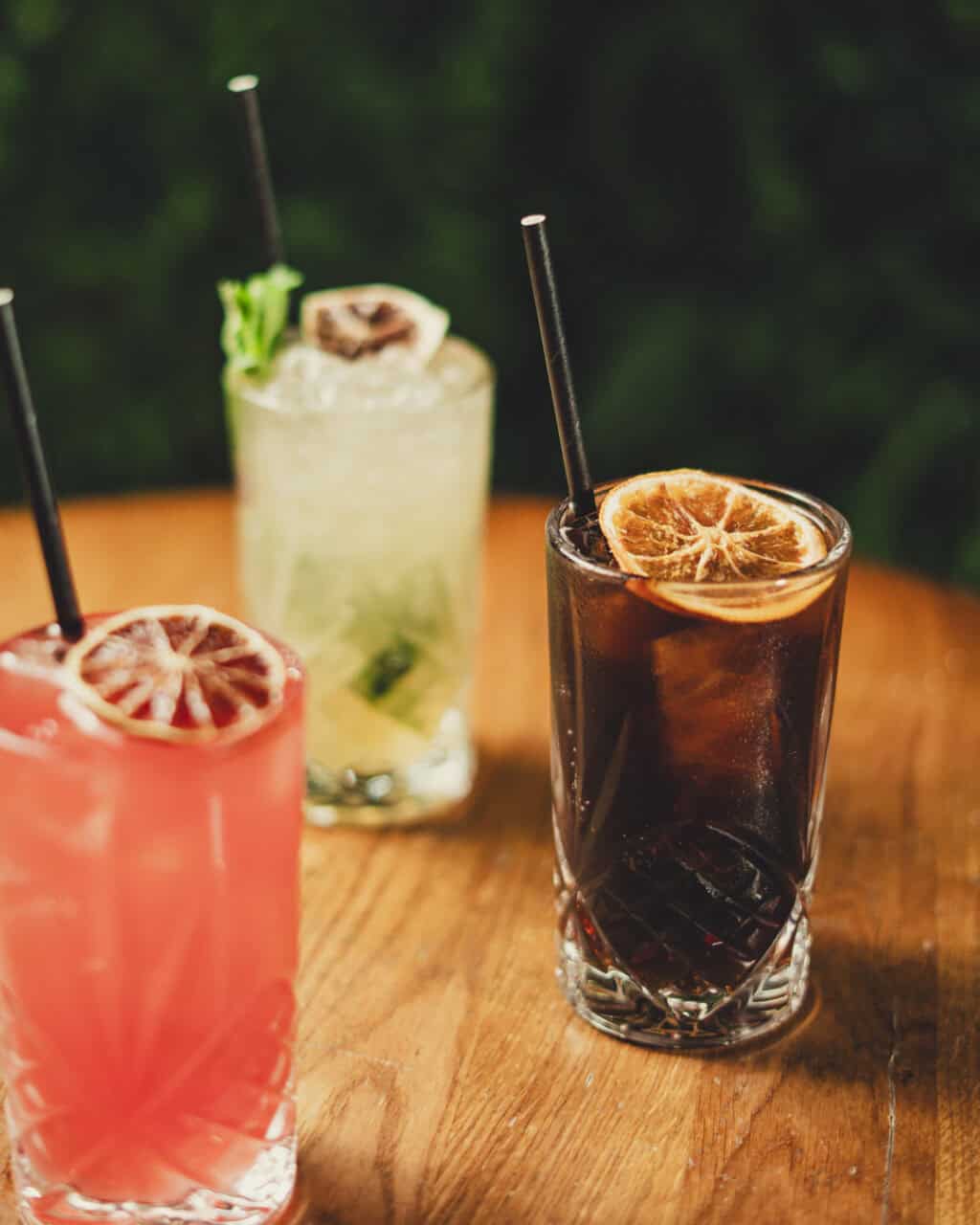 Cocktails with citrus slices and ice on a wooden table, perfect for a relaxing drink.