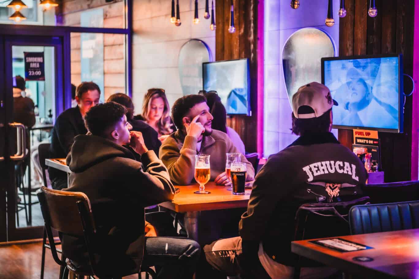 Group of young people enjoying drinks and socialising at London Bridge Hostel lounge.