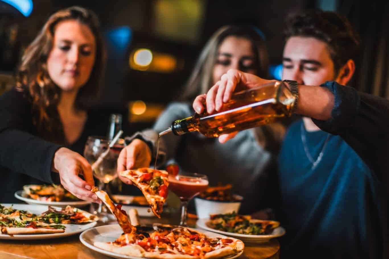 Pizza night at a lively restaurant with friends enjoying drinks and sharing food.