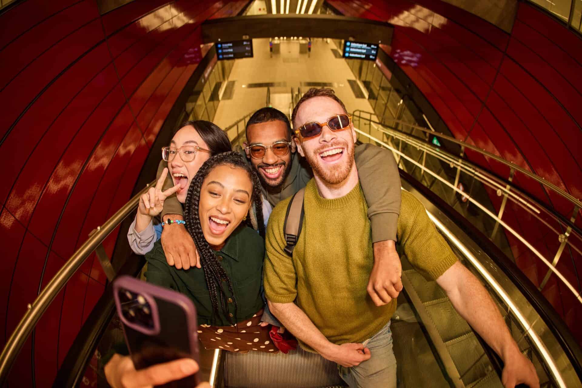Group of happy friends taking a selfie at Liverpool Street Hostel staircase.