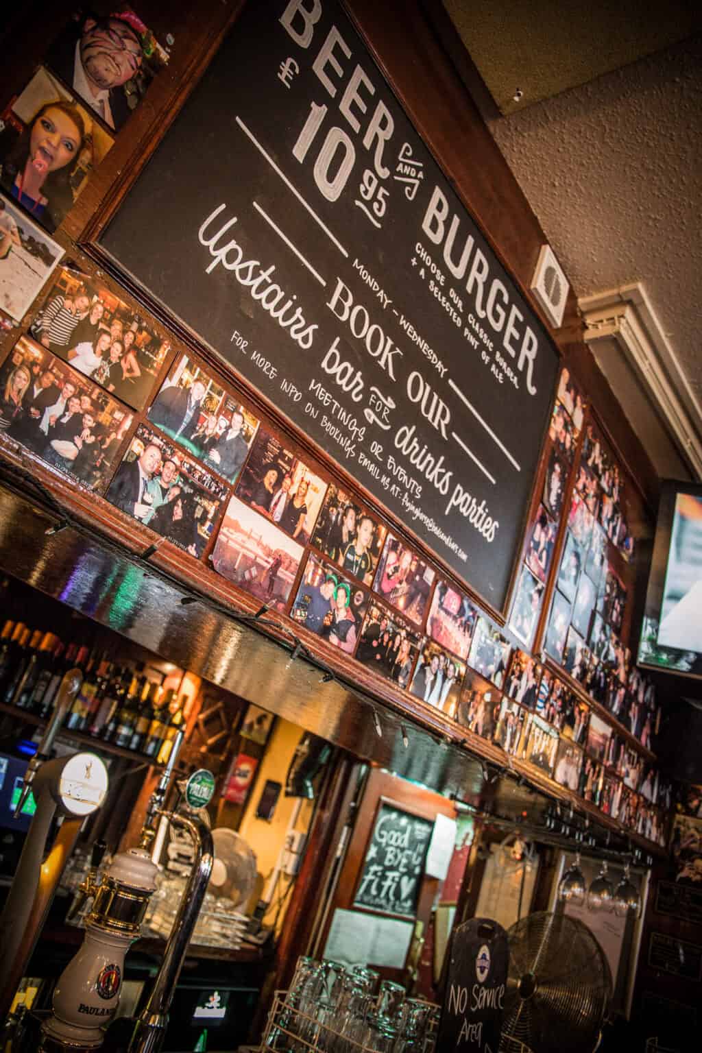Interior view of Liverpool Street Hostel bar with photos and drink offerings.