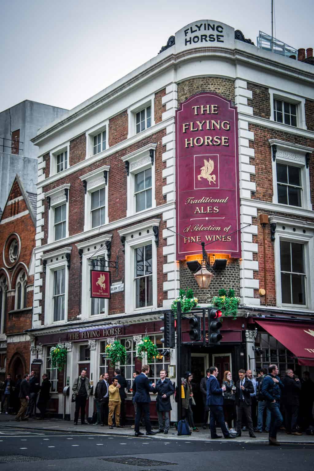 Flying Horse pub exterior with people waiting outside.