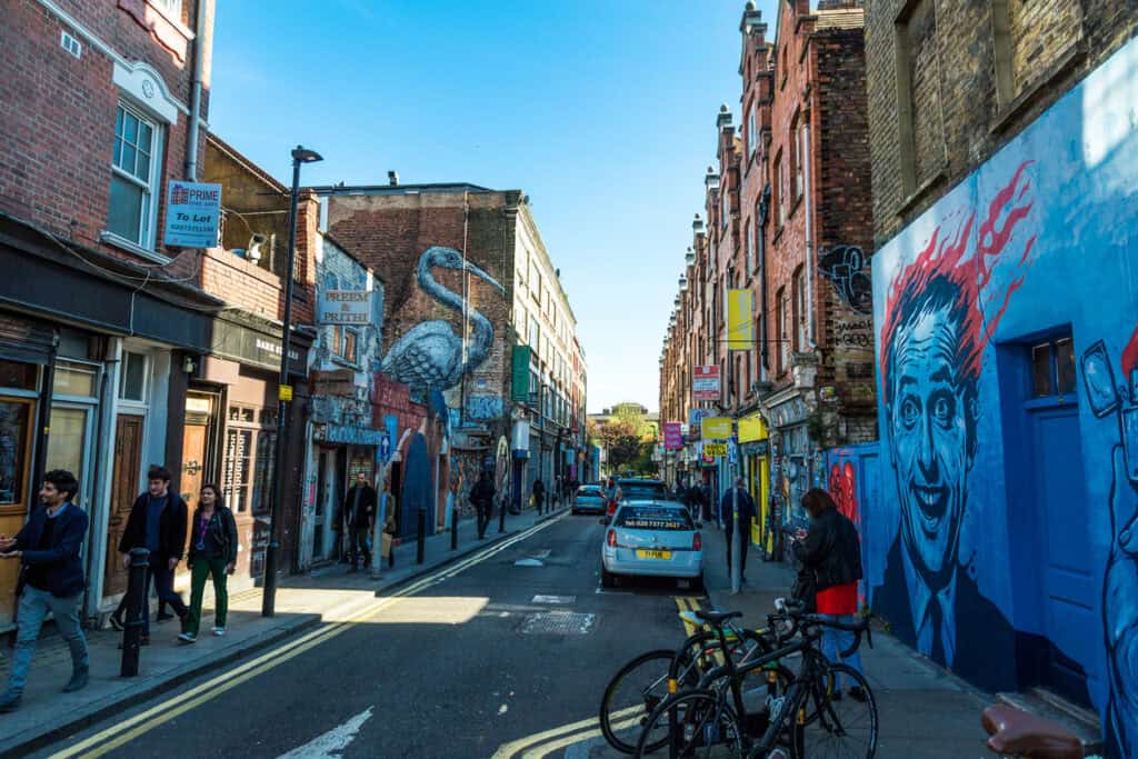 Bright street scene outside St Christopher’s Liverpool Street Hostel with colourful murals and pedes.