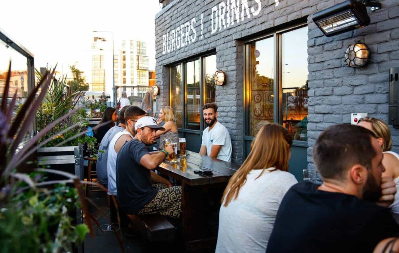 Group of people enjoying drinks on the outdoor terrace at St Christopher's Shepherd's Bush.