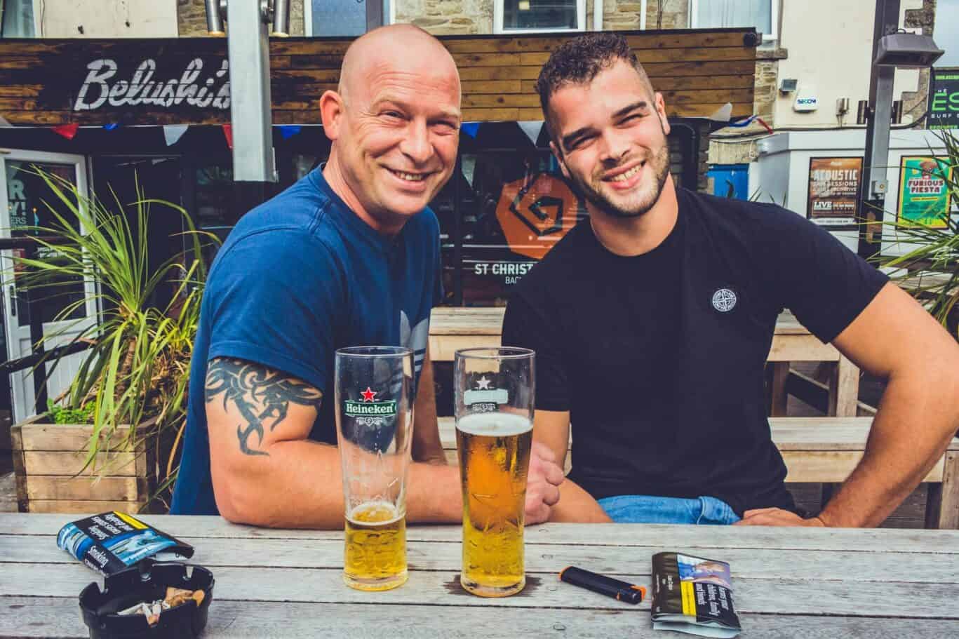 Two men enjoying drinks outside St Christopher’s Newquay hostel in Cornwall.