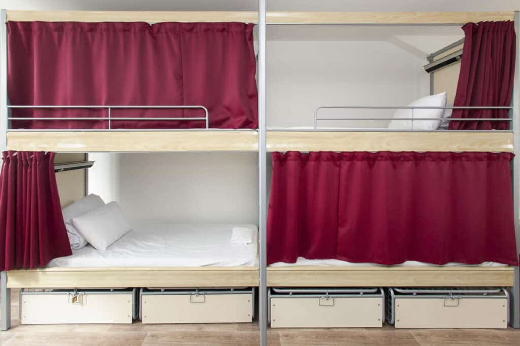 Bunk beds with red curtains and white bedding at St Christopher’s Paris - Gare du Nord.