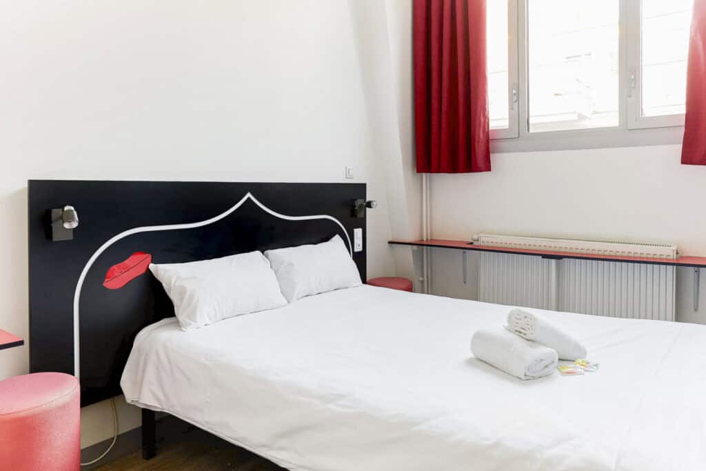 Modern hostel room with a double bed and colourful decor.