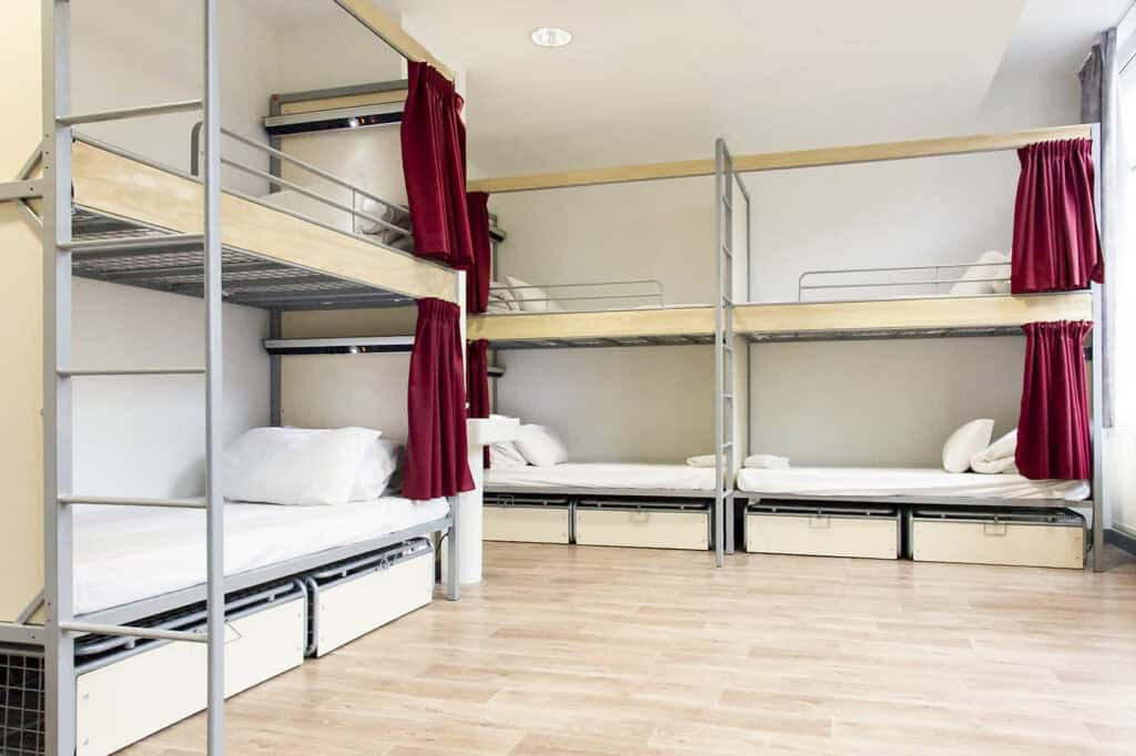 Bunk beds with privacy curtains in a modern hostel dormitory, Paris.
