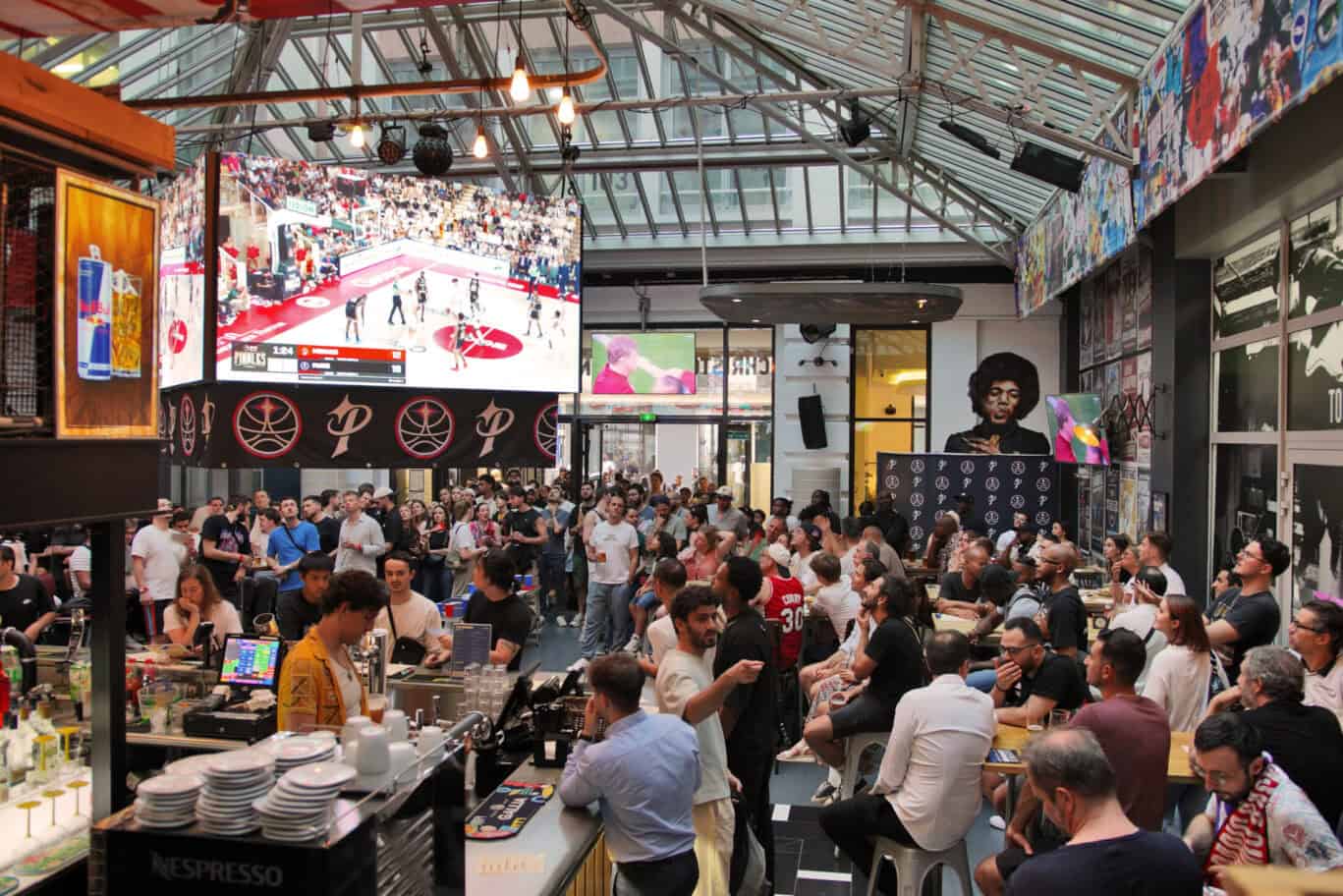 Indoor sports bar bustling with patrons watching a hockey game on large screens.