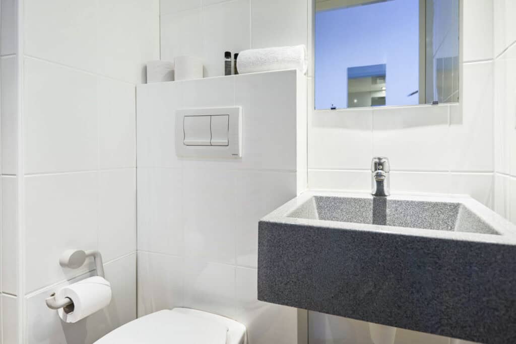 Clean and minimalist bathroom featuring a grey sink and white tiled walls at Gare du Nord hostel, Pa.