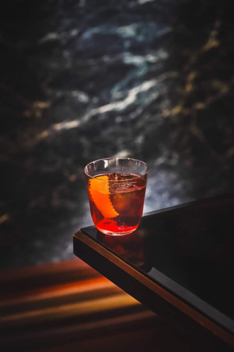 Classic Americano Cocktail with an Orange Peel Garnish Served in a Glass on a Dark Elegant Surface, Highlighting a Timeless Italian Aperitif