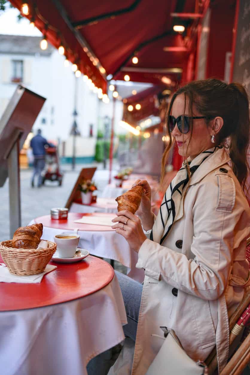 Outdoor café with a woman enjoying breakfast in Paris.