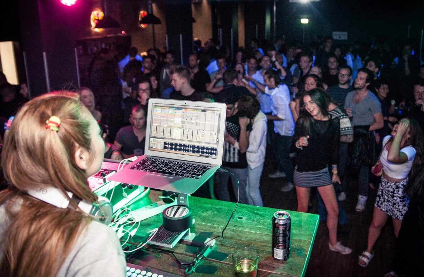 DJ performing at a lively nightclub with a crowd dancing and enjoying music at Gare du Nord hostel i.
