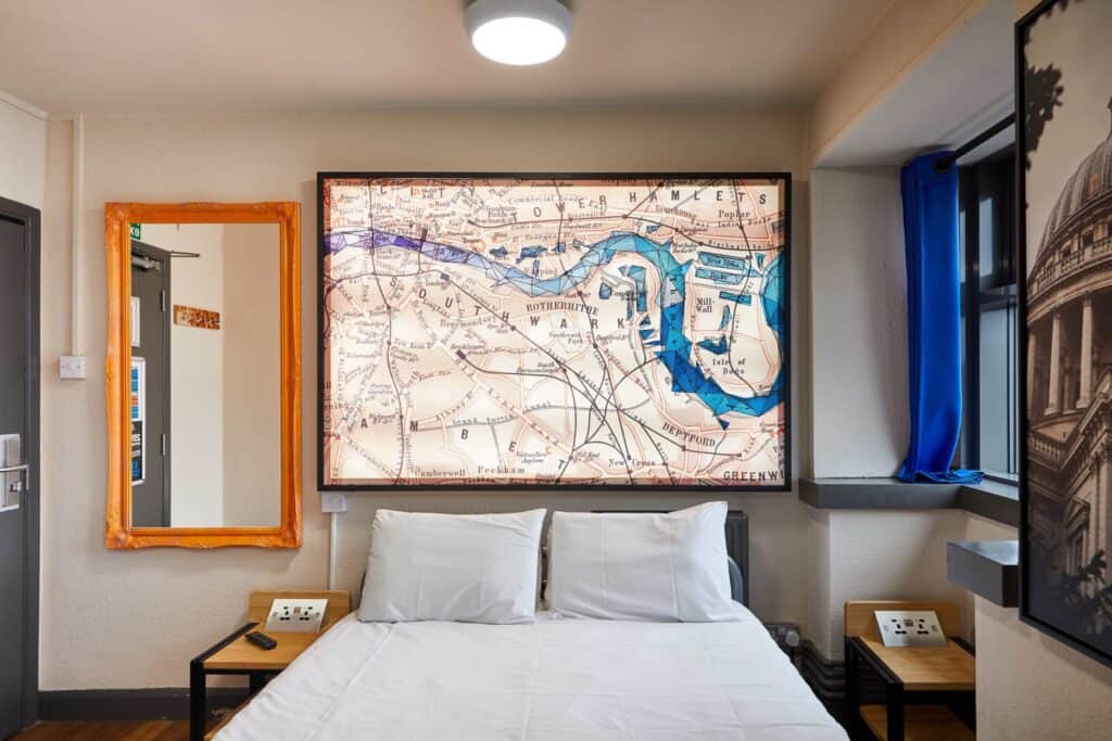 Cozy bedroom at Shepherd's Bush Hostel with map artwork and en suite facilities.