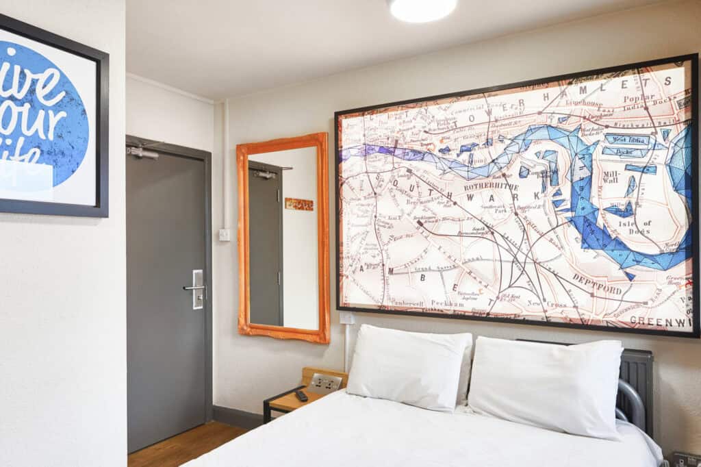 Modern hostel room with map artwork and en suite facilities in Shepherd's Bush.