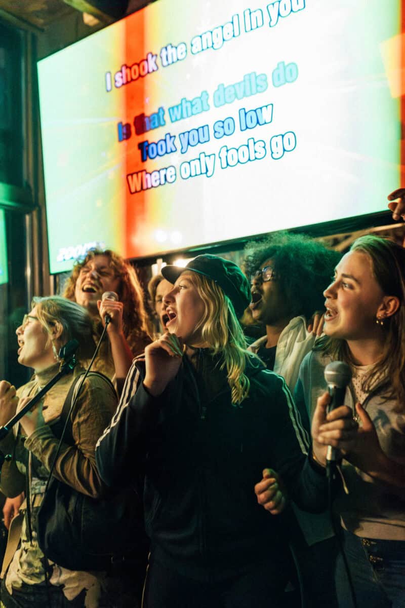 Group of young people singing and enjoying at Shepherd's Bush Hostel event.