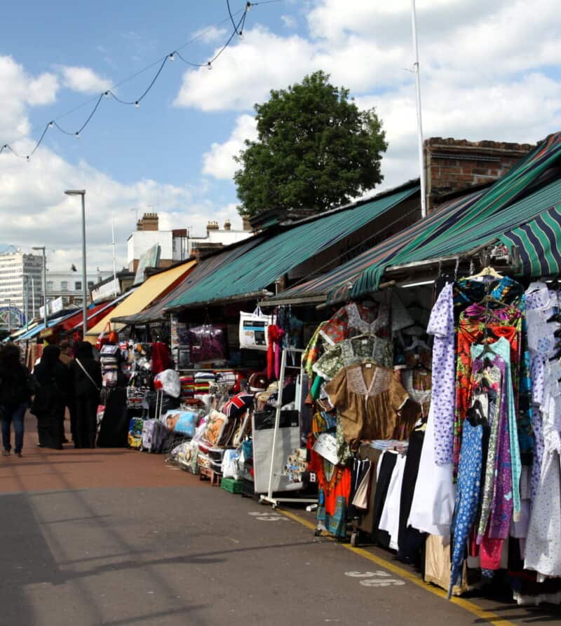 Outdoor market stalls in Shepherd's Bush with clothing and accessories on display.