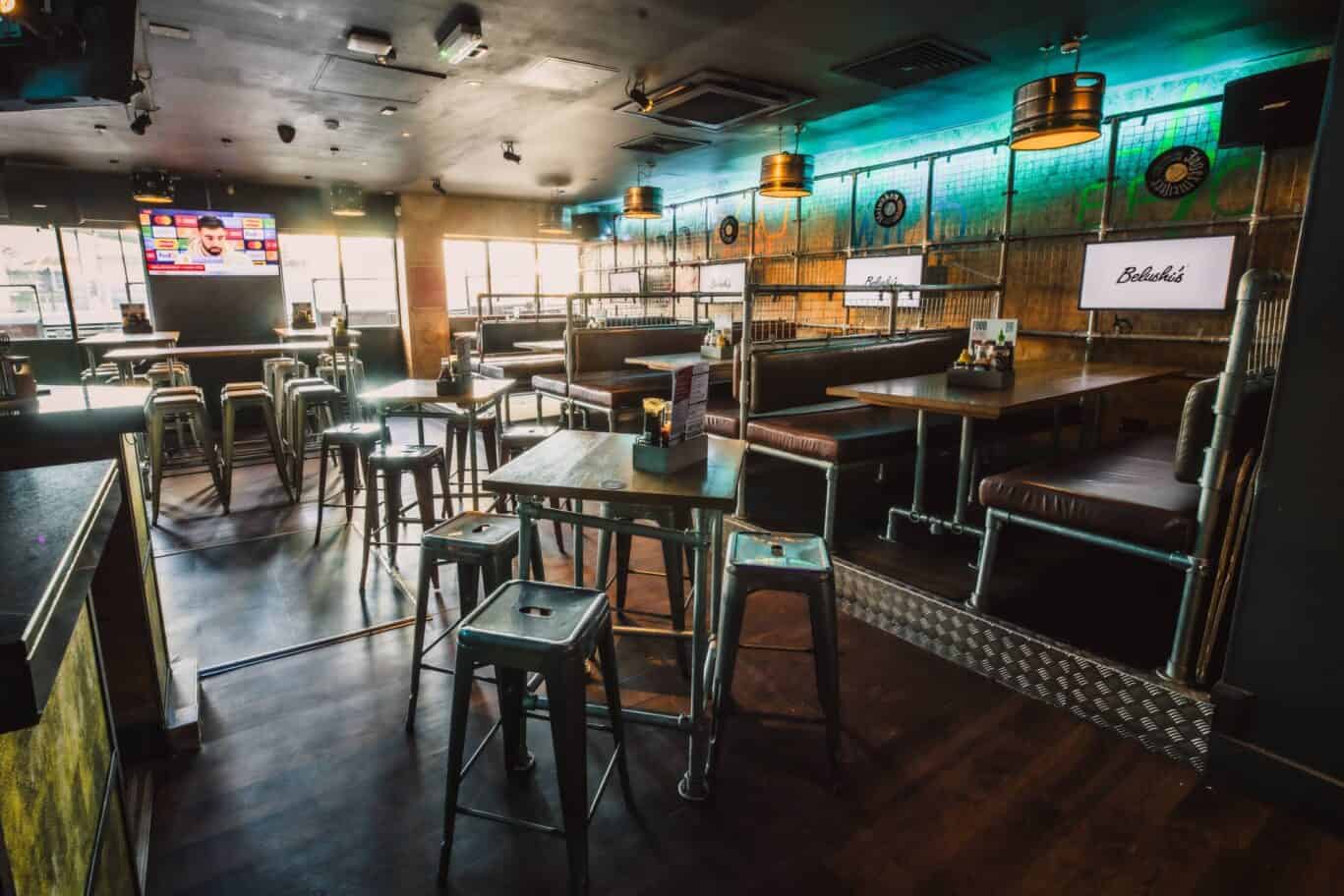 Modern hostel bar interior with seating and large screen TV.