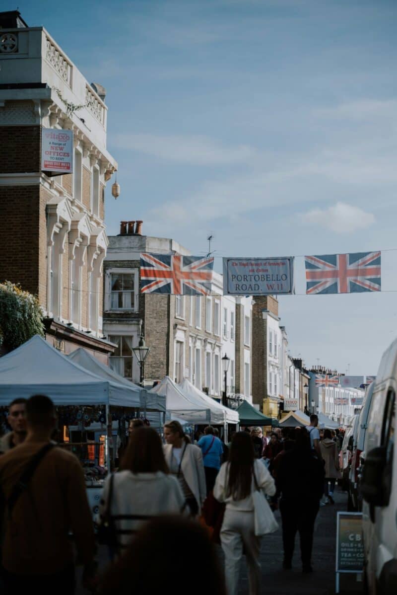 Street scene in Shepherd's Bush with market stalls and UK flags overhead.
