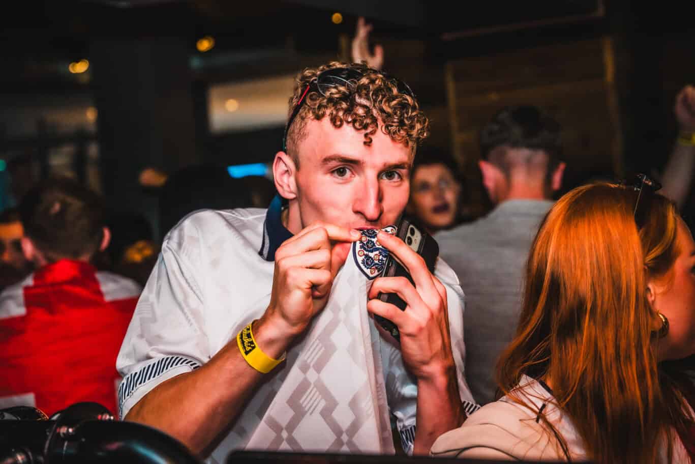 Young man enjoying a drink in a lively bar setting.