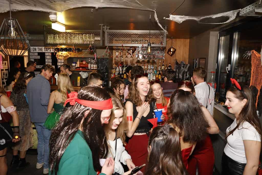 Lively social scene at St Christopher’s Vienna hostel bar with young guests enjoying drinks and conv.
