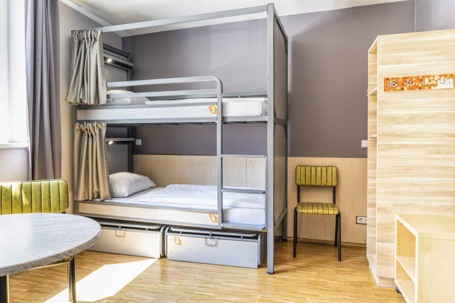 Bunk beds in a contemporary hostel room at St Christopher’s Vienna, featuring a seating area and nat.