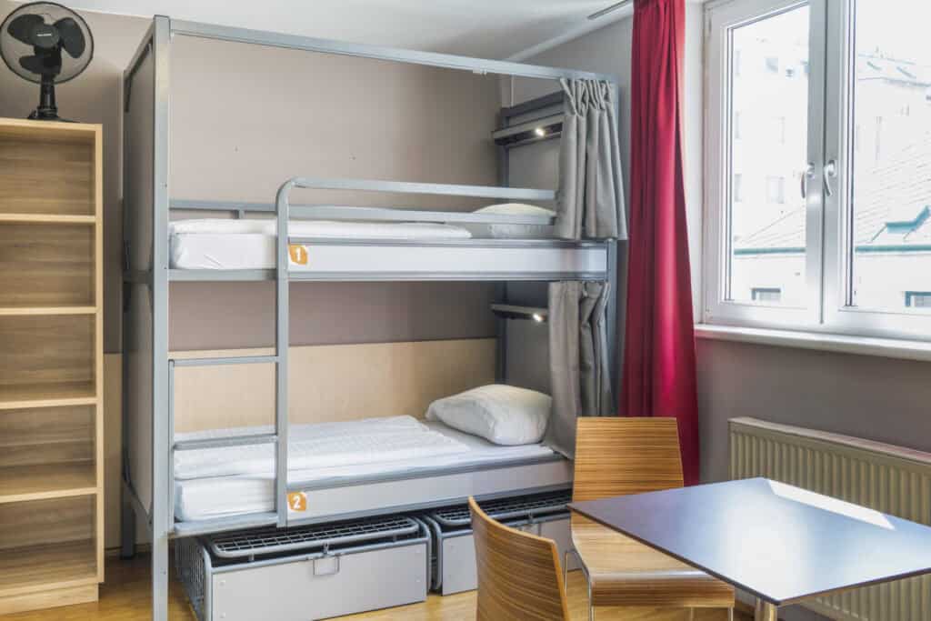 Bunk beds in a hostel dorm room at St Christopher’s Vienna, with a study table and window view.
