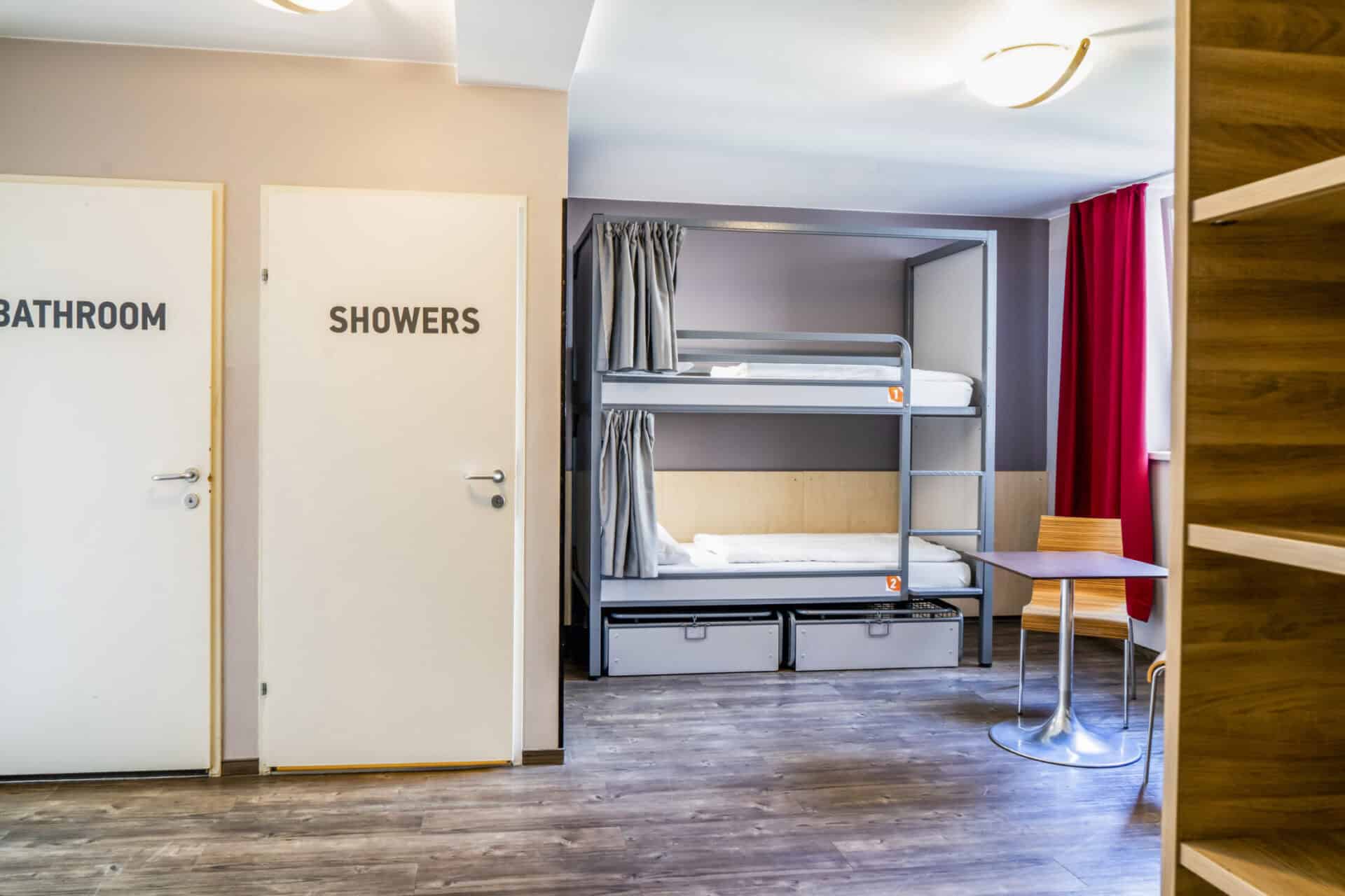 Modern hostel room with bunk beds, desk, and storage at St Christopher’s Vienna.