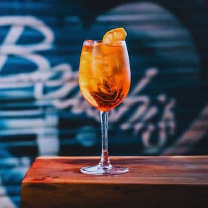 Aperol Spritz cocktail with orange slice served in a tall glass at St Christopher’s Vienna Hostel.