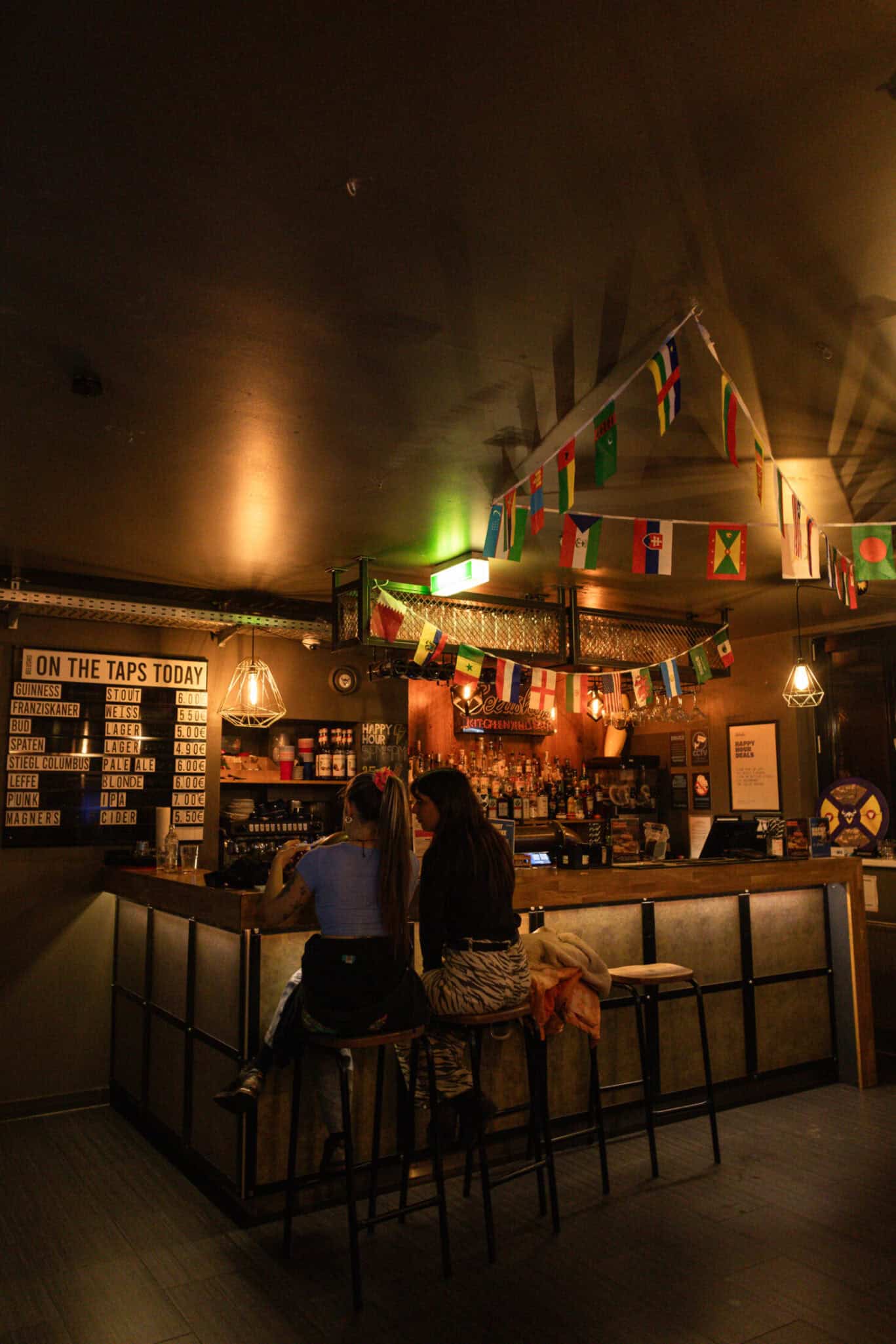 Hostel bar with colourful flags and warm lighting in Vienna.