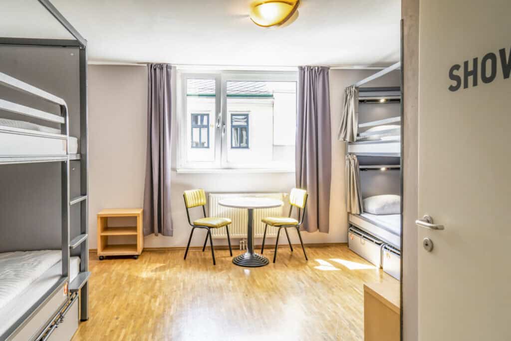 Modern hostel dorm room with bunk beds and a small seating area in Vienna.