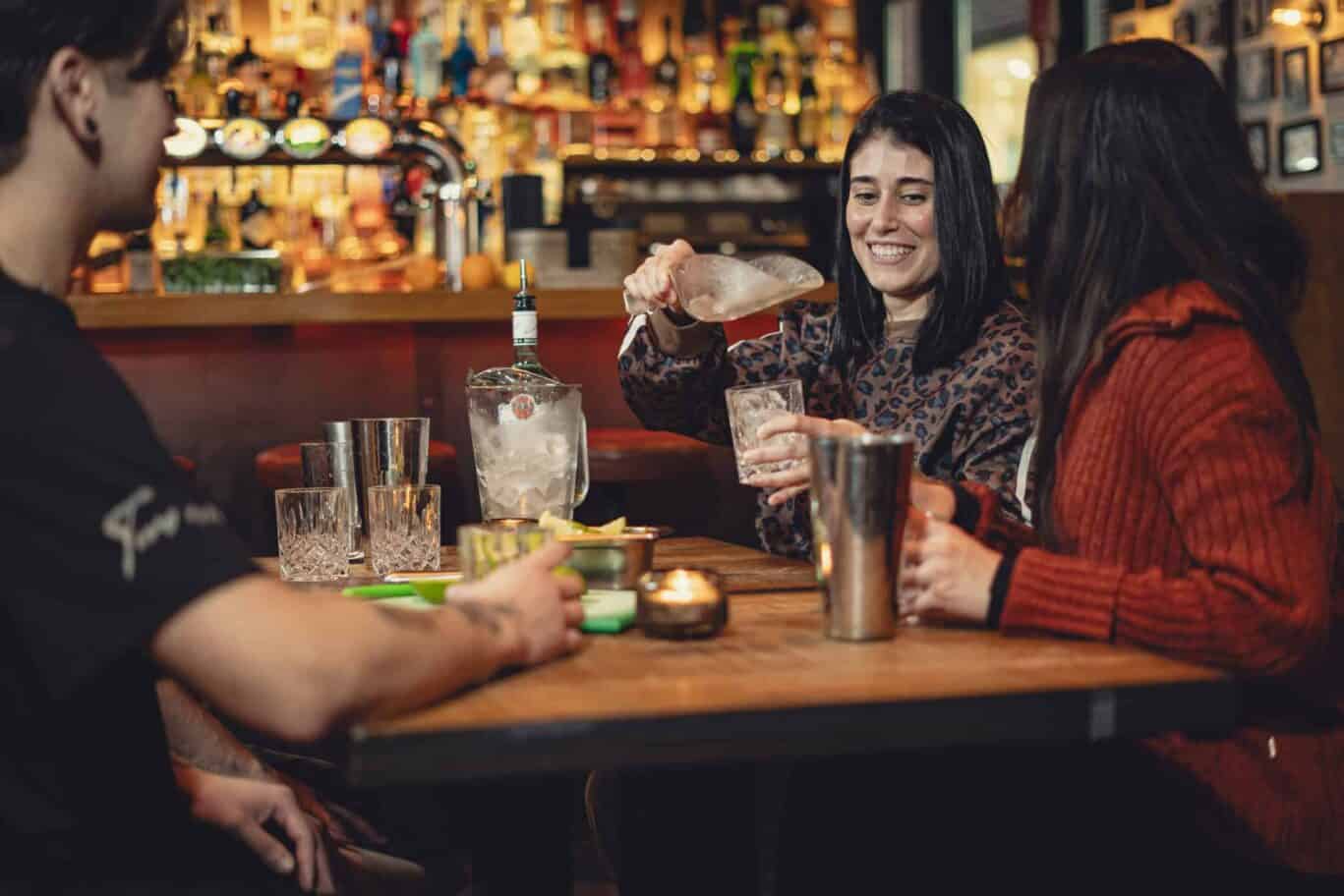 Group of friends enjoying drinks at a lively bar in Vienna Hostel, socialising and having fun.