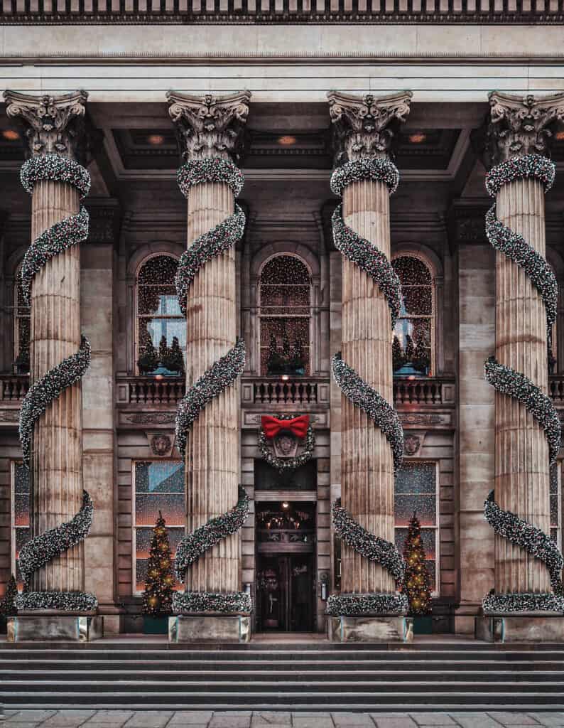 Historic Berlin building decorated for Christmas with festive garlands and Christmas trees.