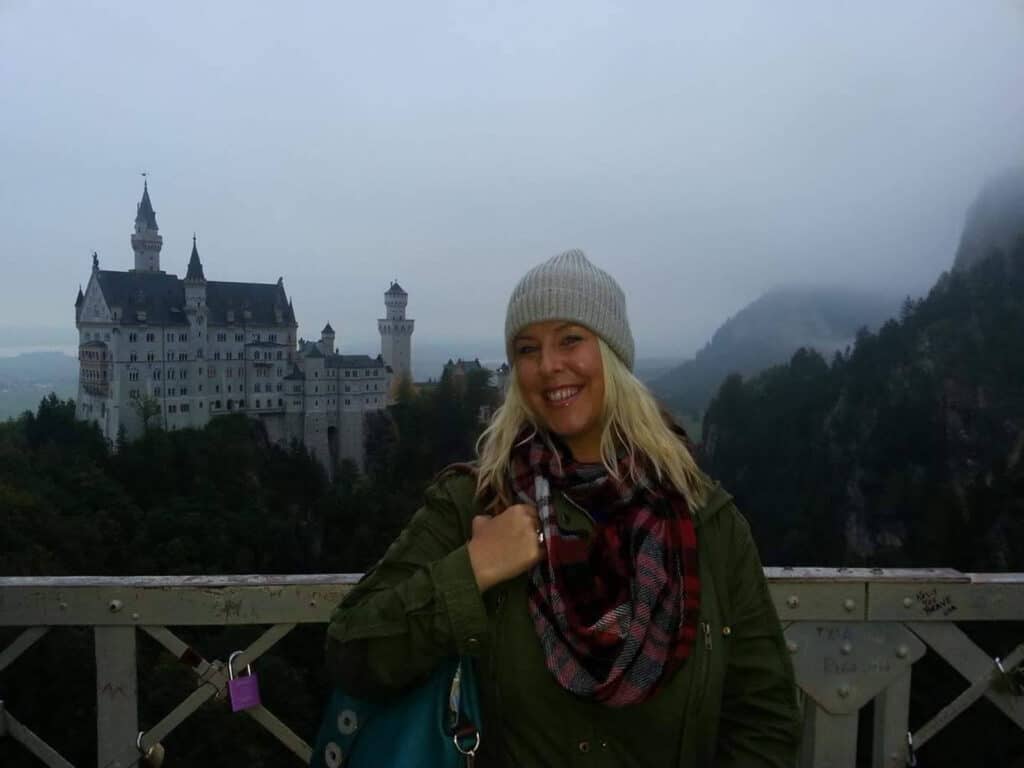 Woman smiling at Mitte Hostel with Neuschwanstein Castle in the background, Berlin.