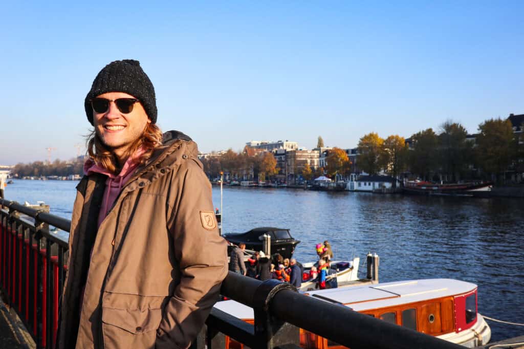 A smiling woman in a brown jacket and black beanie enjoying the view along the Berlin River.