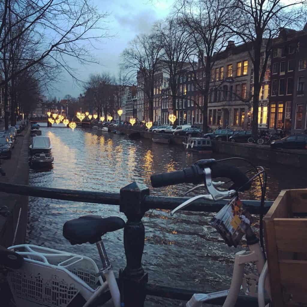 View of canal in Berlin with bicycles and historic buildings at dusk.