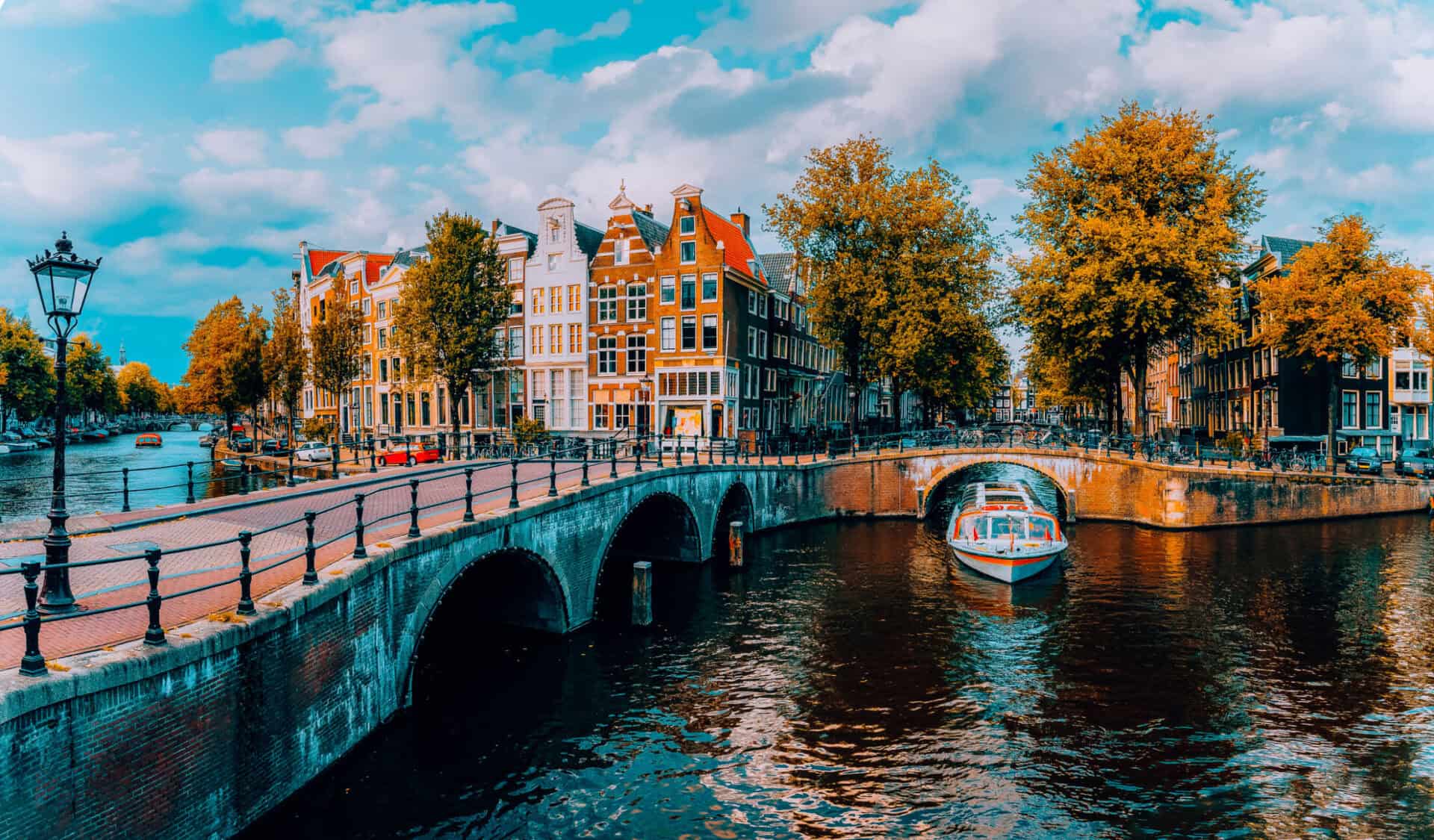 Bright view of Mitte hostel along a canal in Berlin, with historic buildings and autumn trees.