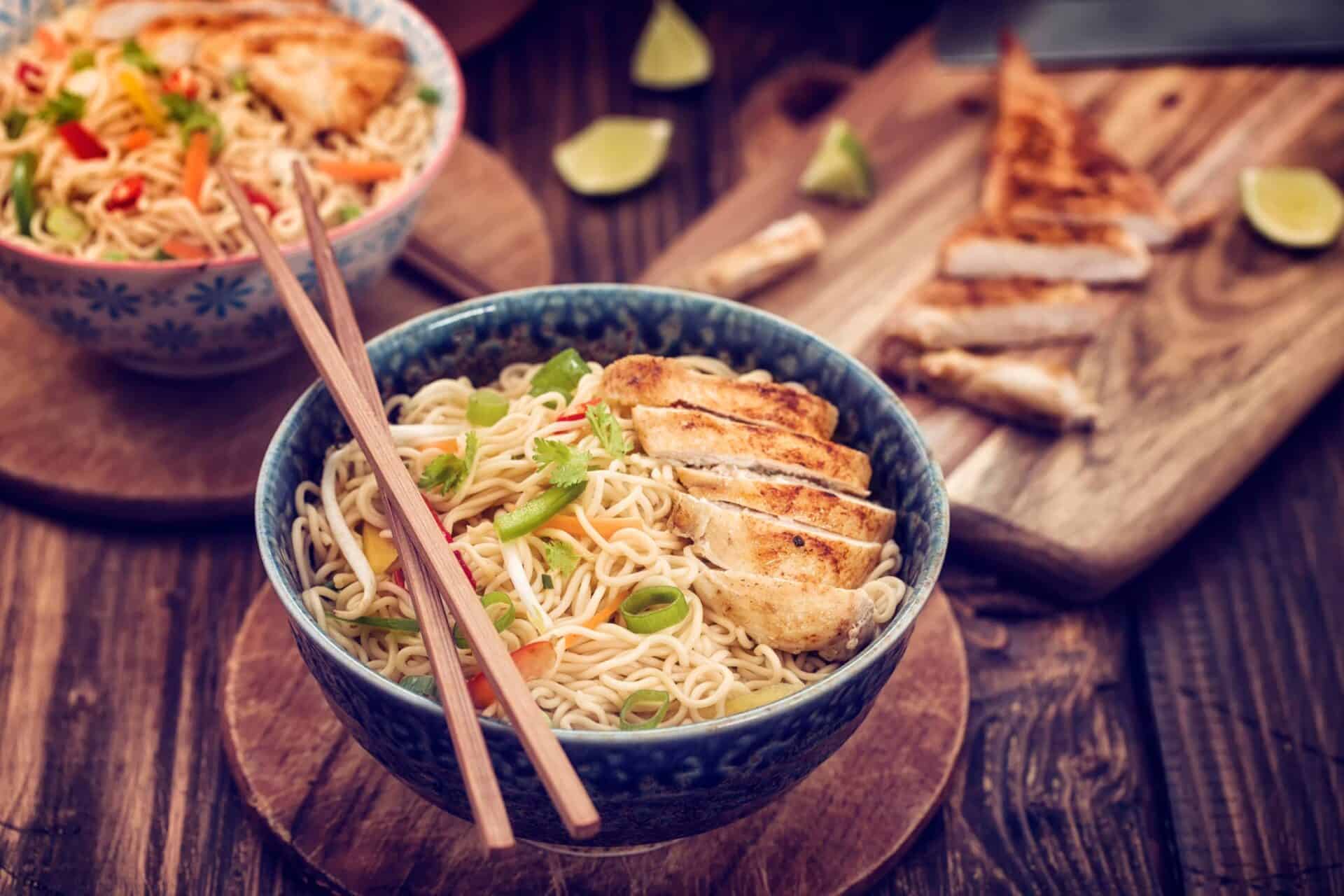 Delicious Asian-style noodle bowl featuring grilled chicken, fresh vegetables, and herbs, served wit.